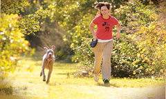 Dog Park A woman running with a dog.